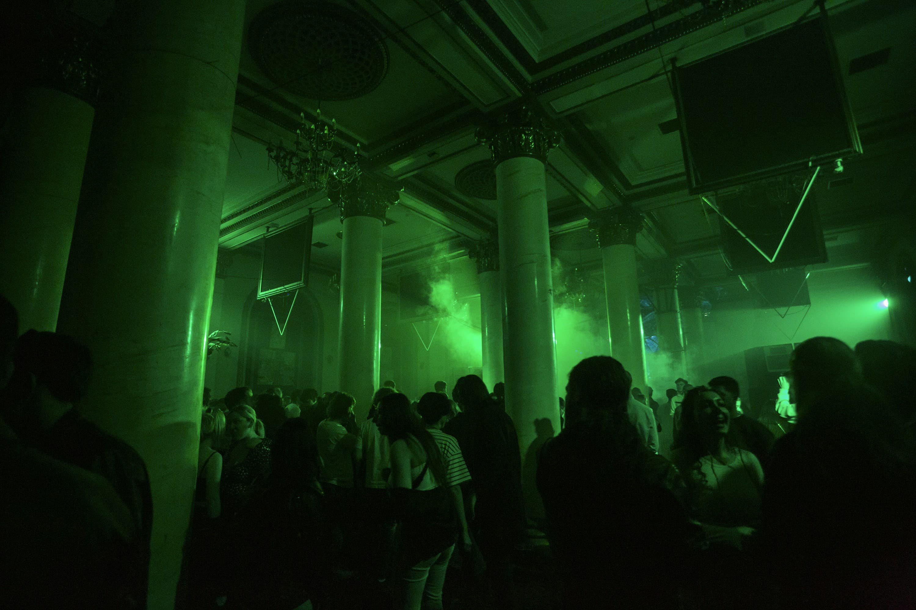 Crowded dance floor with people dancing under colorful disco lights and smoke effects
