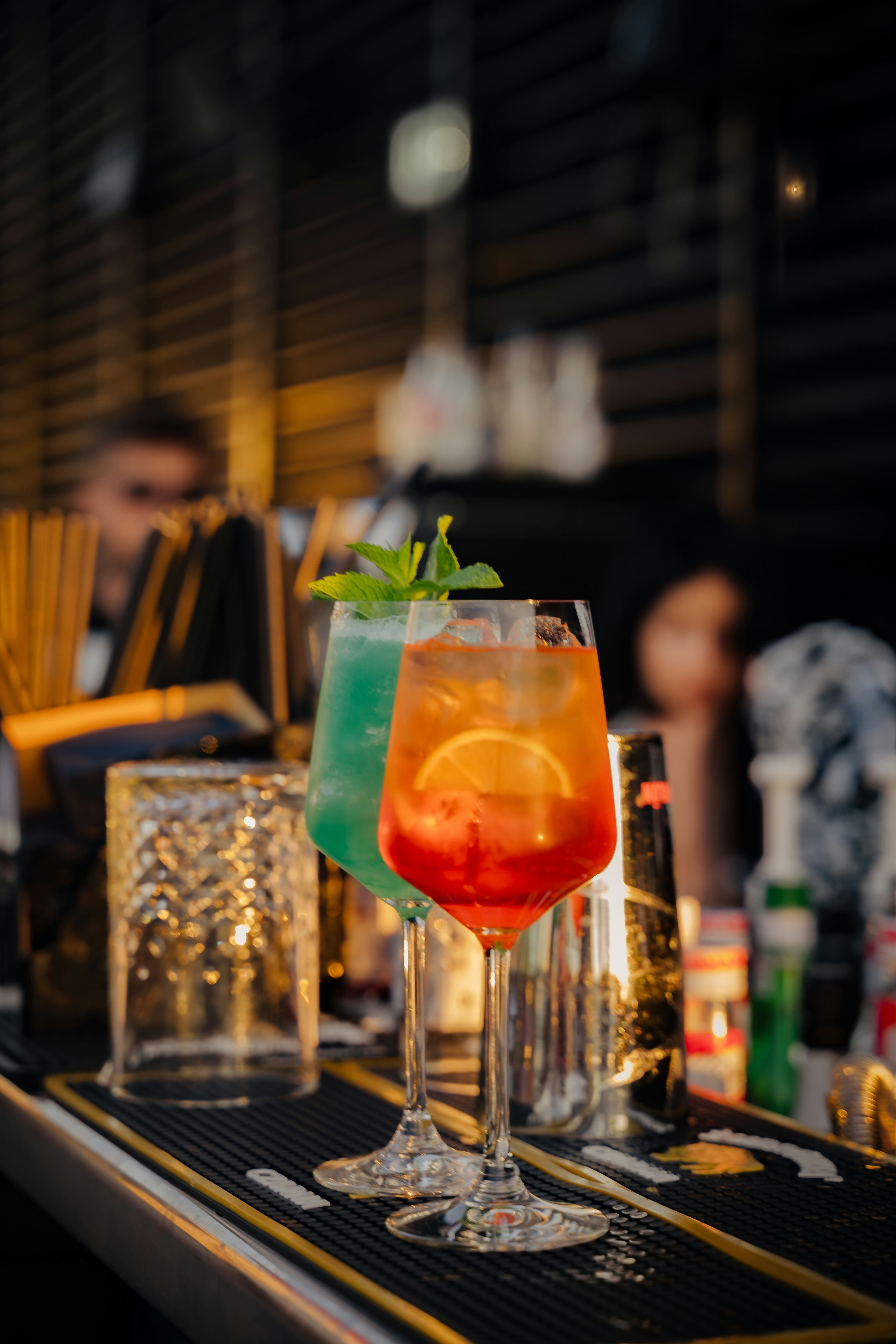 Colorful cocktails with garnishes on dark bar counter with ambient lighting