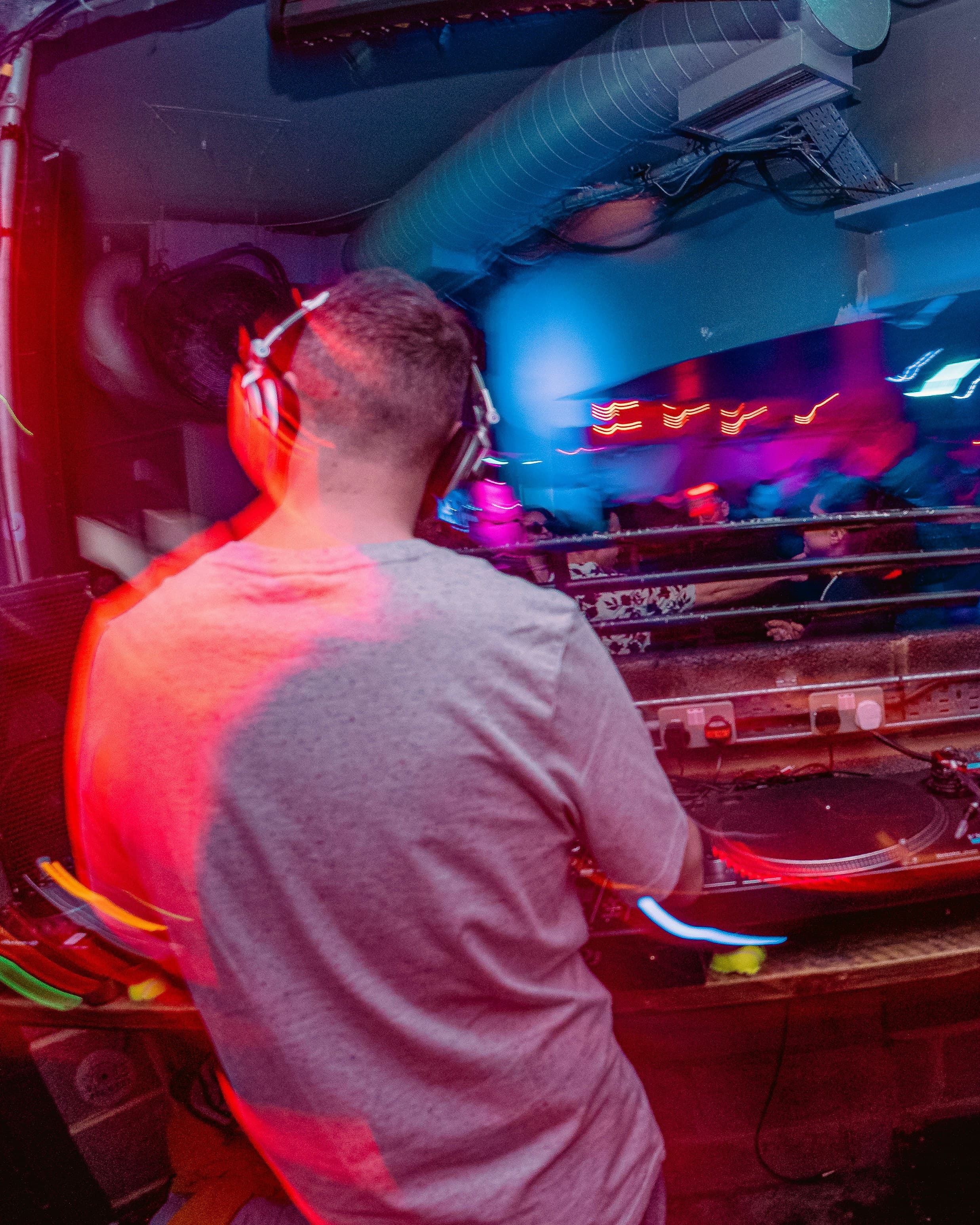 Professional DJ with headphones performing at turntables with colorful stage lights